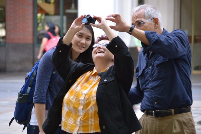 three people taking photo outside