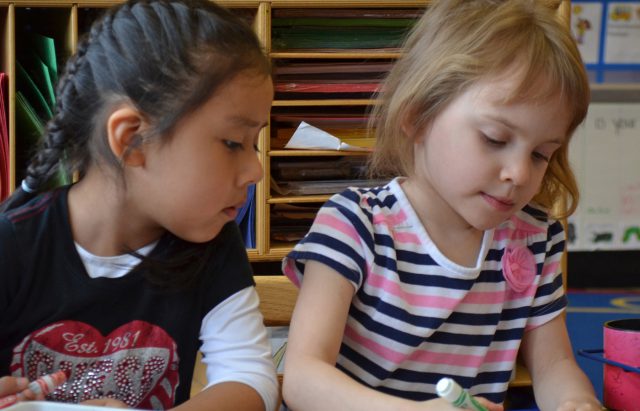 Two young girls drawing with markers.